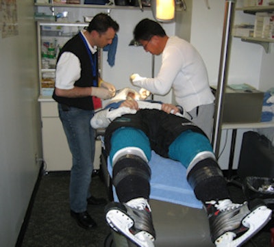 Dr. Donald L. Goudy Jr. and Arthur Ting, MD, orthopedic surgeon and head physician for the San Jose Sharks, work on a player who's still wearing his skates.