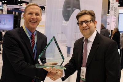 DrBicuspid.com CEO Craig Overpeck (right) presents Dentsply Sirona CEO Don Casey with a Dental Excellence Award at the Dentsply Sirona booth at the Midwinter Meeting.