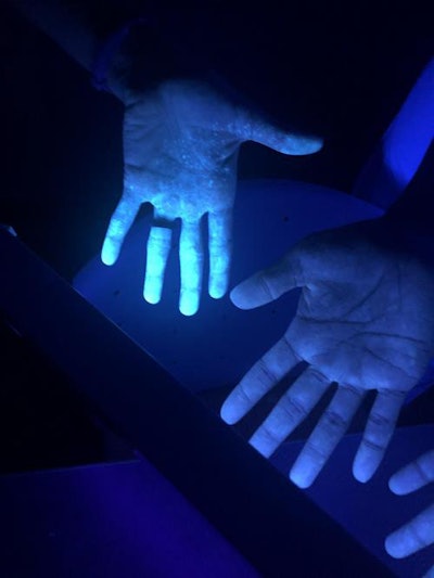 Ultraviolet light shows the presence of fluorescent solution on the skin, representing an exposure to the contagion.
