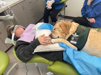 A Labrador retriever named Atkins sits on Levi McAllister's lap as he gets two teeth pulled. Image courtesy of Crouch for Kaiser Health News.
