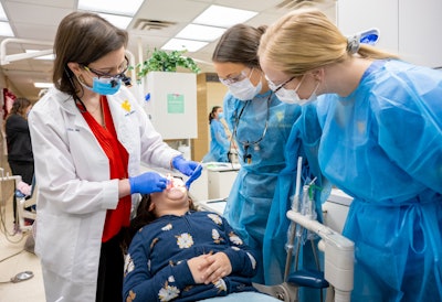 Dr. Gina Graziani (left), chair of the WVU School of Dentistry Department of Pediatric Dentistry, and dental students work with a patient during the Give Kids a Smile event in Morgantown, WV, on February 3, 2023. The school's new residency program in pediatric dentistry will be the first of its kind in West Virginia. Image courtesy of WVU/Davidson Chan.