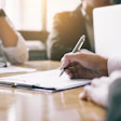Business professionals review documents at conference table.