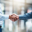 Two men shake hands, representing a business agreement.