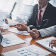Business professionals analyze financial charts and data during a meeting.