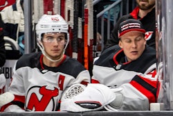 Hughes (pictured left) on the Devils bench during a December 2023 game.