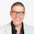 Professional headshot of a smiling man wearing glasses and a light blazer over a dark shirt Headshot