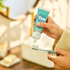 Close-up of a person applying Tom's of Maine toothpaste to a toothbrush.