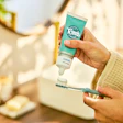 Close-up of a person applying Tom's of Maine toothpaste to a toothbrush.