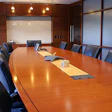 Modern conference room with a cherry wood table, leather chairs, a white board, and large windows.