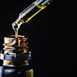Golden liquid is dispersed from a dropper into an amber glass bottle.