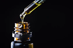 Golden liquid is dispersed from a dropper into an amber glass bottle.