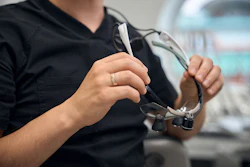 Close-up of a male dentist preparing to put on loupes.