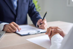 Two professionals review documents during a business meeting, representing formal discipline.