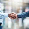 Two male business professionals shake hands.