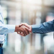 Two male business professionals shake hands.