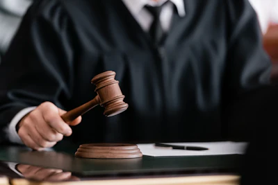 Close-up of a male judge wearing a black robe holding a gavel in his right hand.