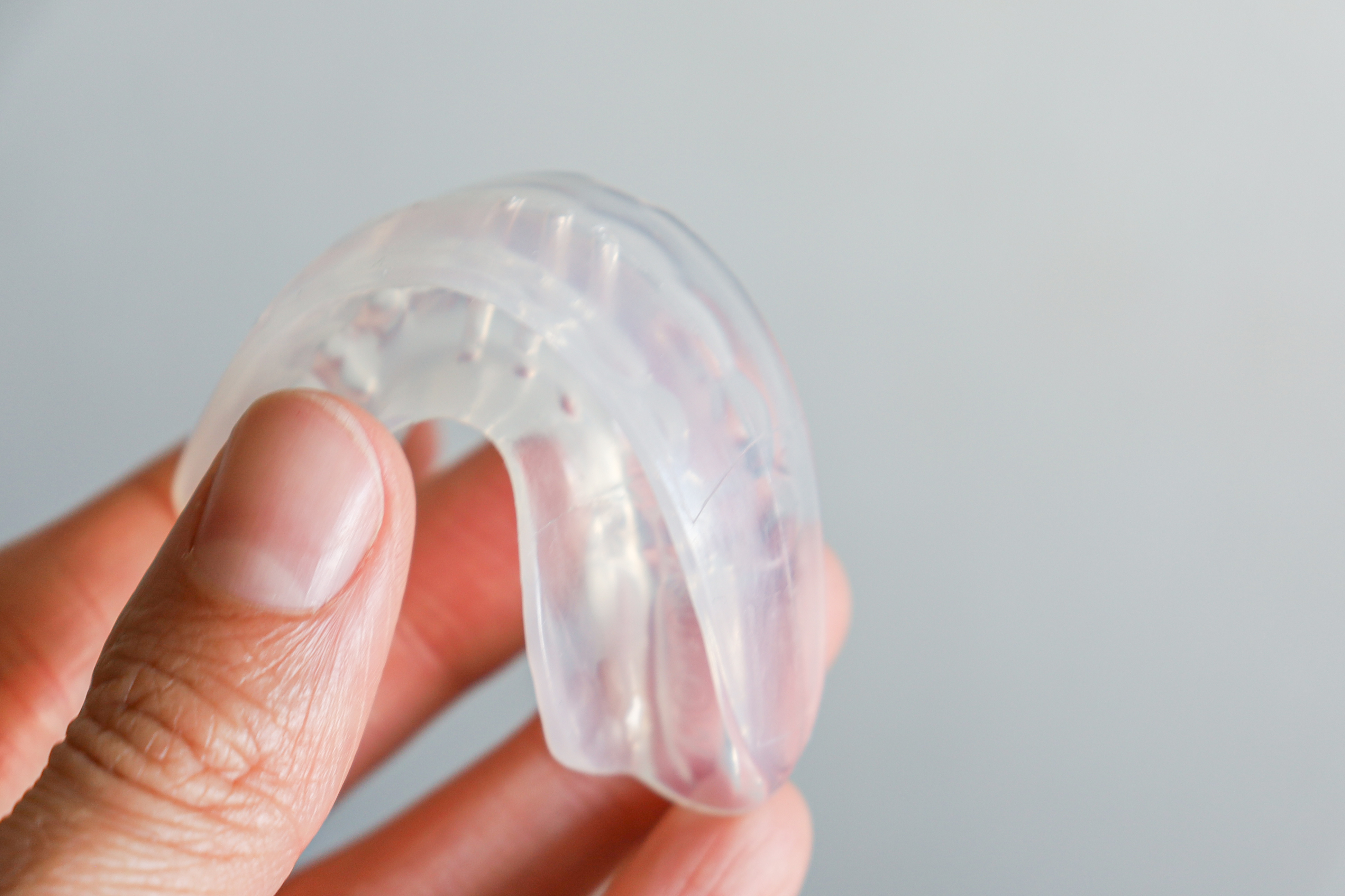 Close-up of a hand holding a clear mouthguard.