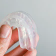 Close-up of a hand holding a clear mouthguard.