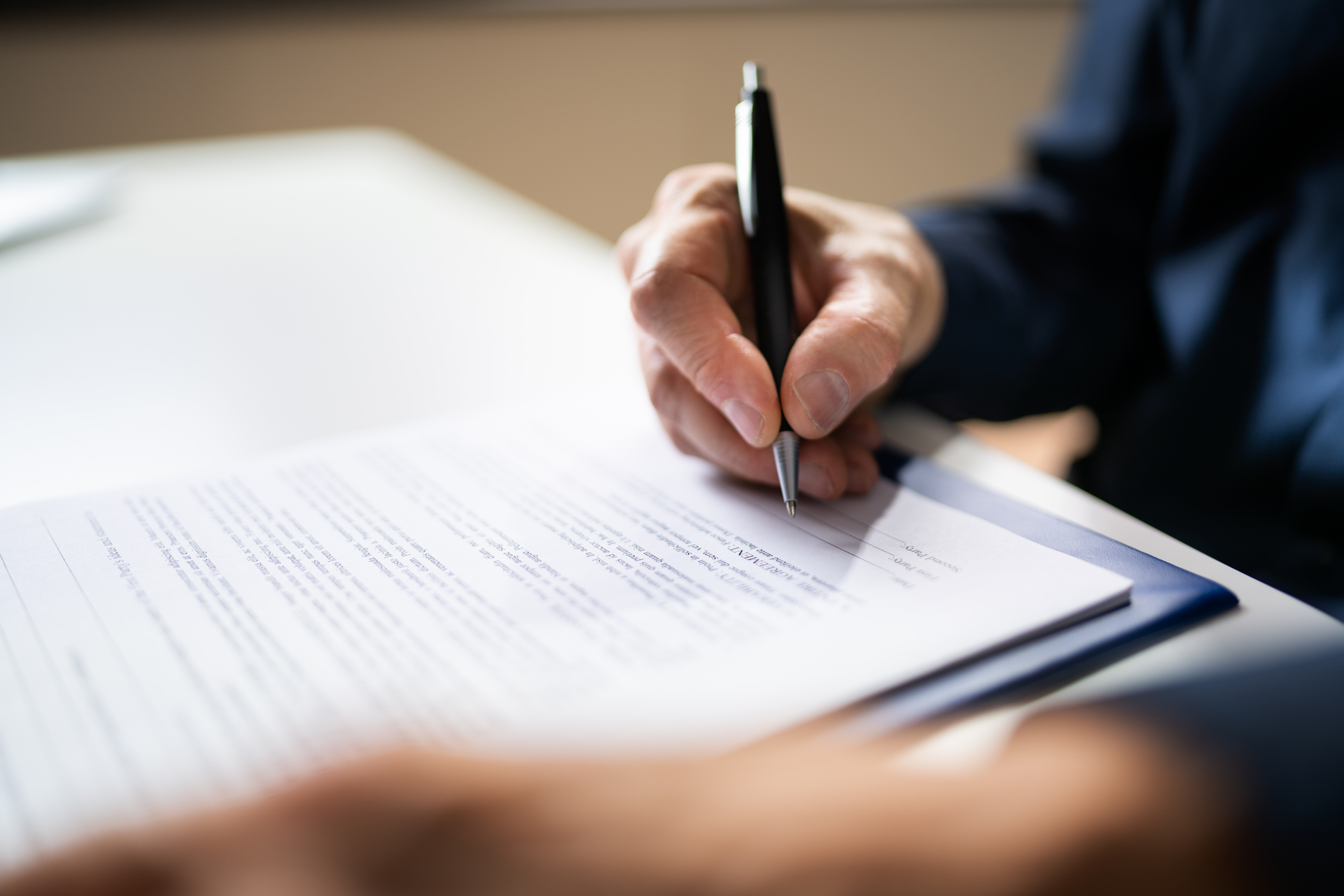 Close-up of a man signing a document.