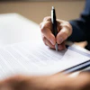 Close-up of a man signing a document.