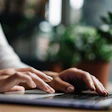 Close-up of a woman's hands typing on a laptop computer.