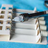 A dental syringe rests on top of vials of clear liquid.
