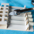 A dental syringe rests on top of vials of clear liquid.
