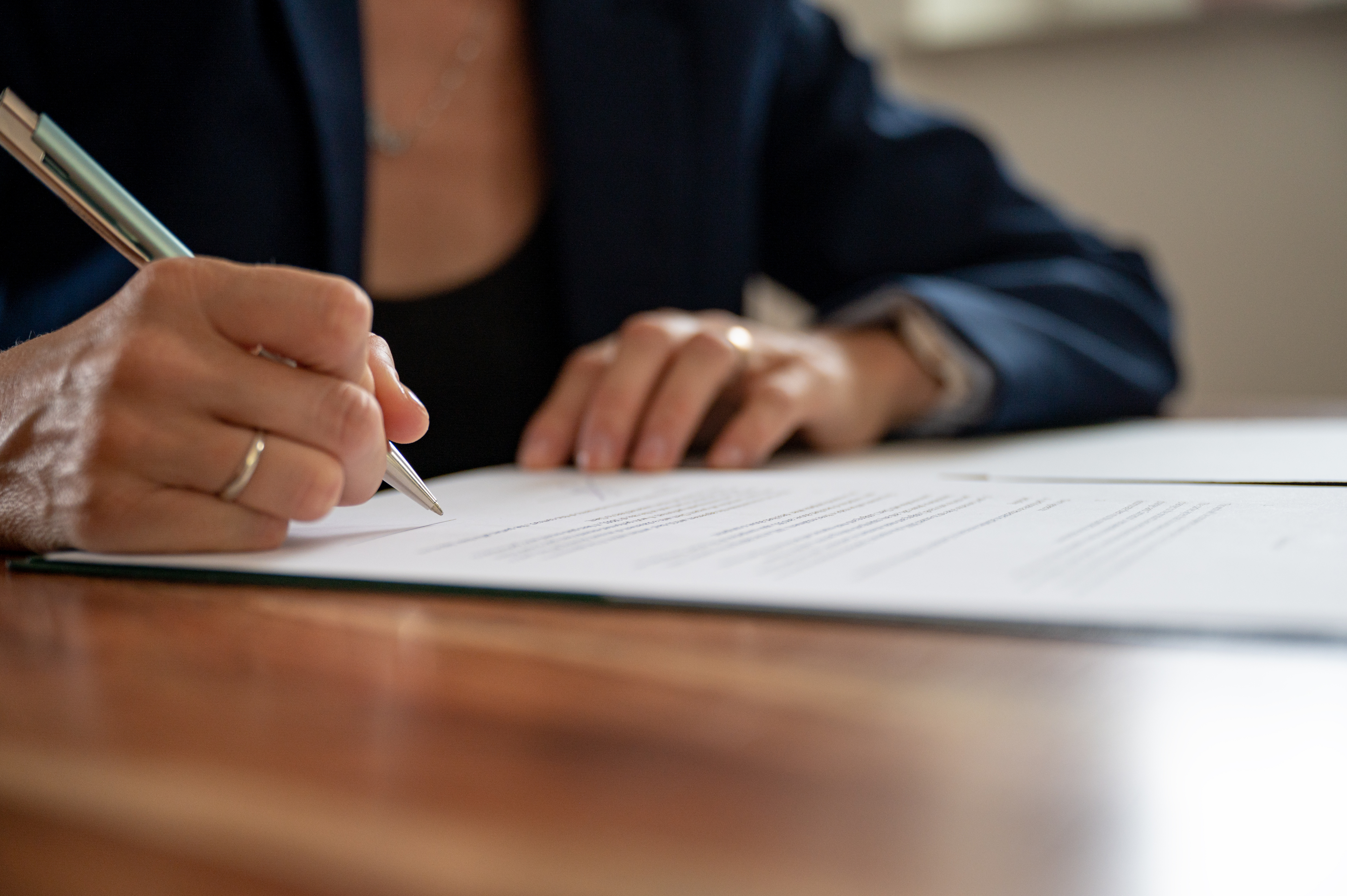 Close-up of a woman signing a document.