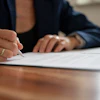 Close-up of a woman signing a document.