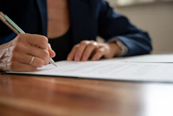 Close-up of a woman signing a document.