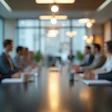 Blurred boardroom meeting with professionals seated around a conference table in a modern office setting.