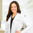 Female doctor in white lab coat smiling at camera in clinical office setting Headshot