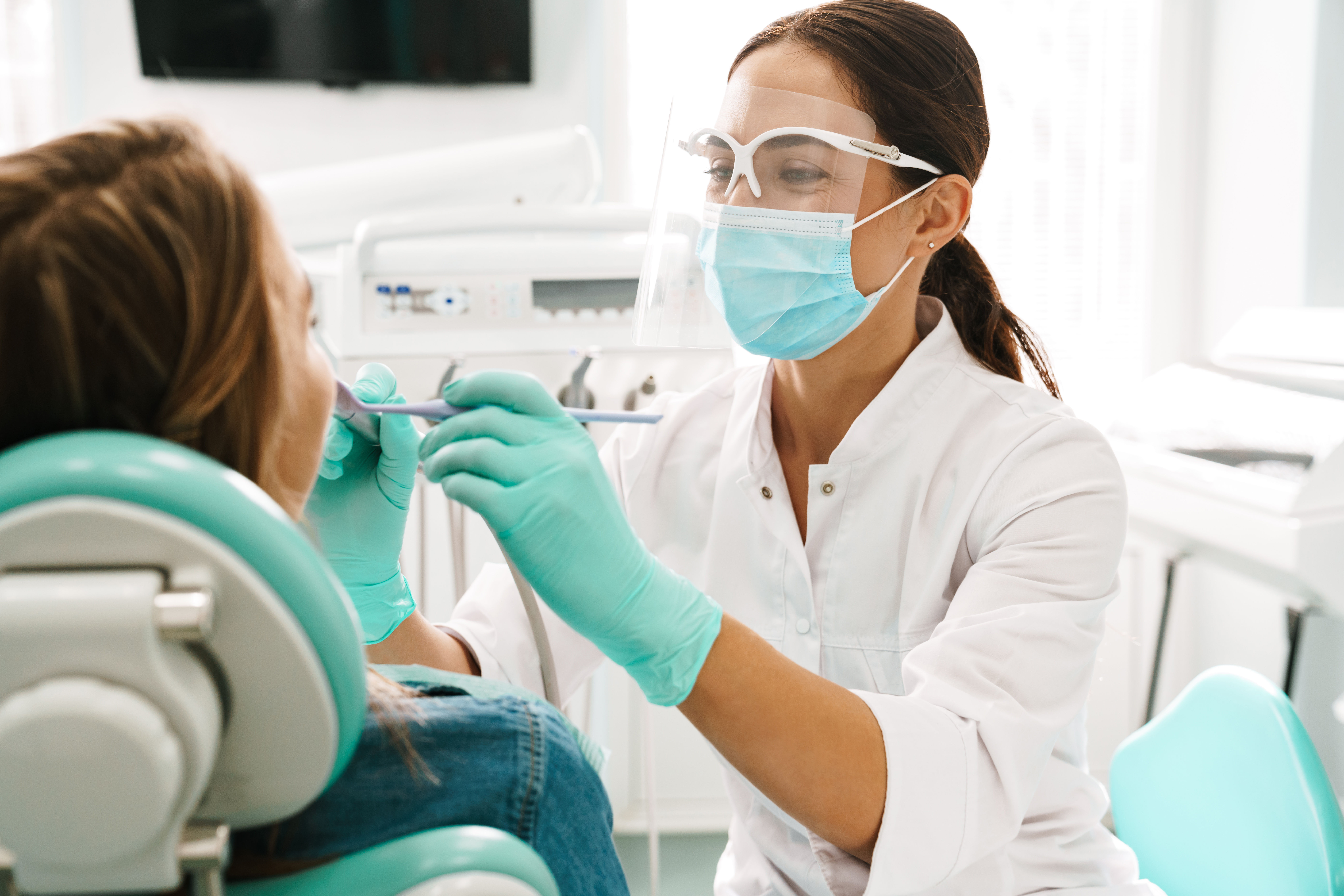 A woman dentist examines a female patient's teeth and mouth.