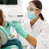 A woman dentist examines a female patient's teeth and mouth.