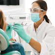 A woman dentist examines a female patient's teeth and mouth.