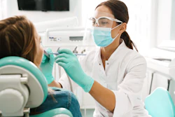 A woman dentist examines a female patient's teeth and mouth.
