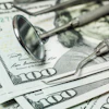 Dental tools lie on top of several $100 bills.
