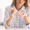 A young woman holds a diabetes lancet to a finger. She is going to perform a blood glucose test.