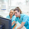 Two dental professionals look at a computer screen. They are troubleshooting a software issue.