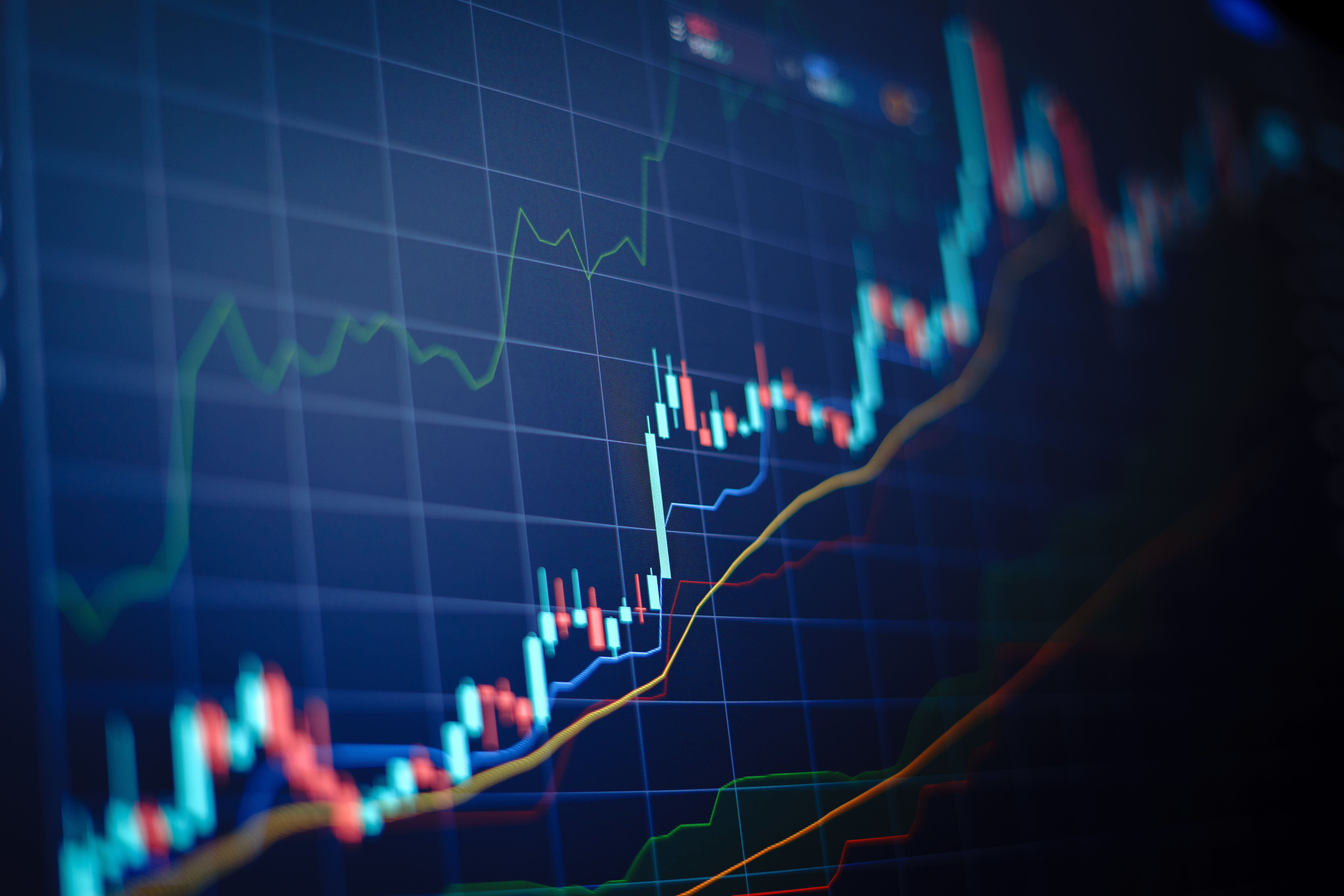 Financial stock market chart with candlestick patterns and colored trend lines on a dark blue grid background.