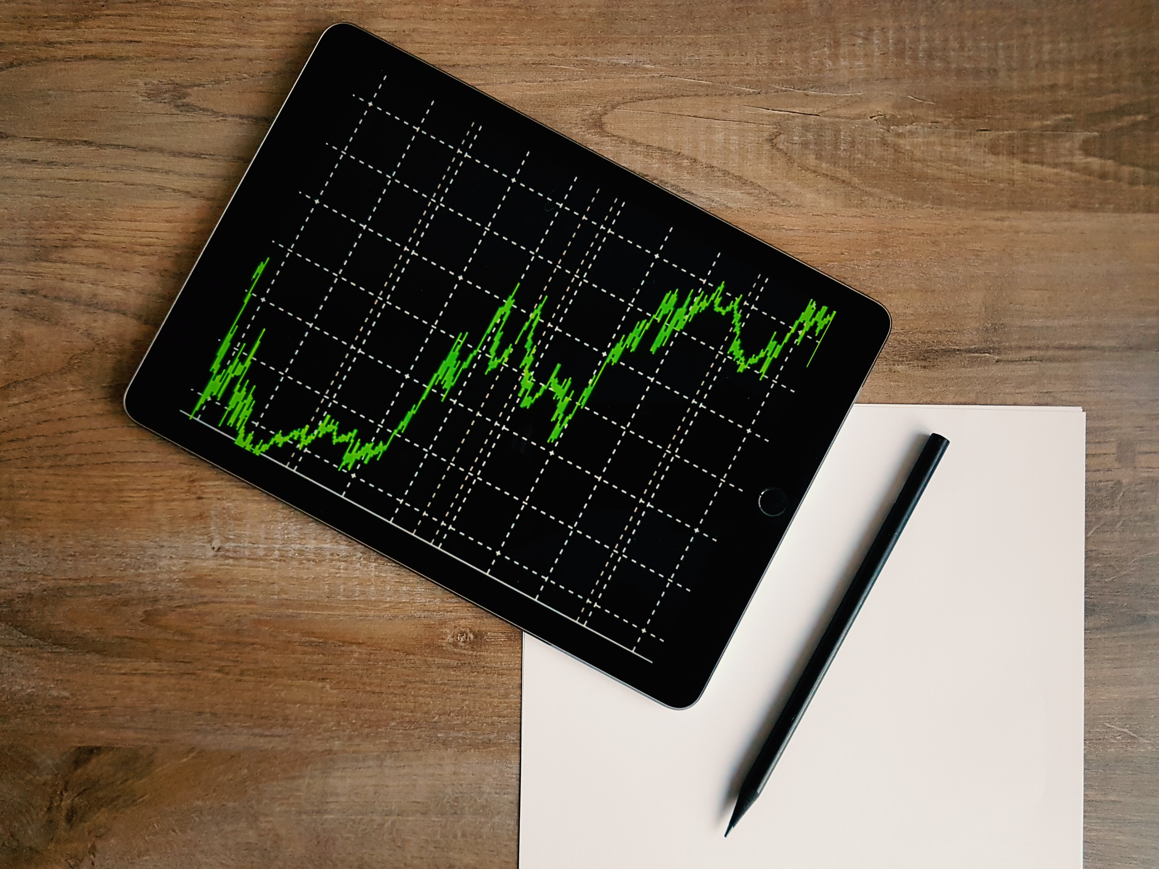 A black computer tablet displays a green financial revenue chart.