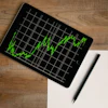 A black computer tablet displays a green financial revenue chart.