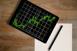 A black computer tablet displays a green financial revenue chart.
