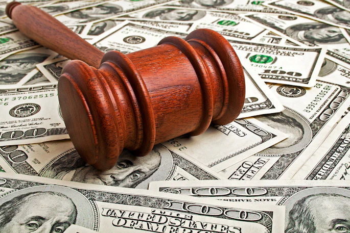 A wood gavel rests on top of several $100 bills.