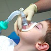 A child has his eyes closed as an anesthesia mask is placed over his nose and mouth.