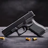 Black semi-automatic handgun with brass ammunition cartridges on a dark surface.