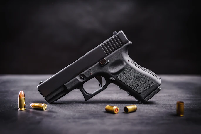 Black semi-automatic handgun with brass ammunition cartridges on a dark surface.