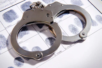 Metal handcuffs rest on top of a fingerprint identification card.