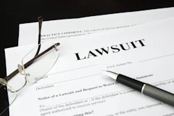 A white document is shown titled 'Lawsuit,' with glasses and a fountain pen resting on top.