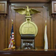 Judge's bench with a gold eagle and legal scales and a wood gavel resting on a counter.